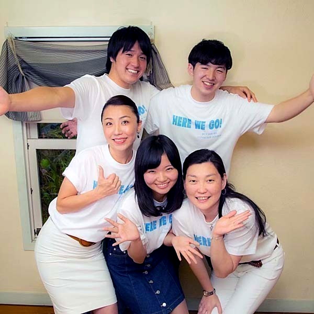 おそろいの「HERE WE GO!」Tシャツを着て笑顔で手を広げる、Fun For Me Language Center のメンバー5人